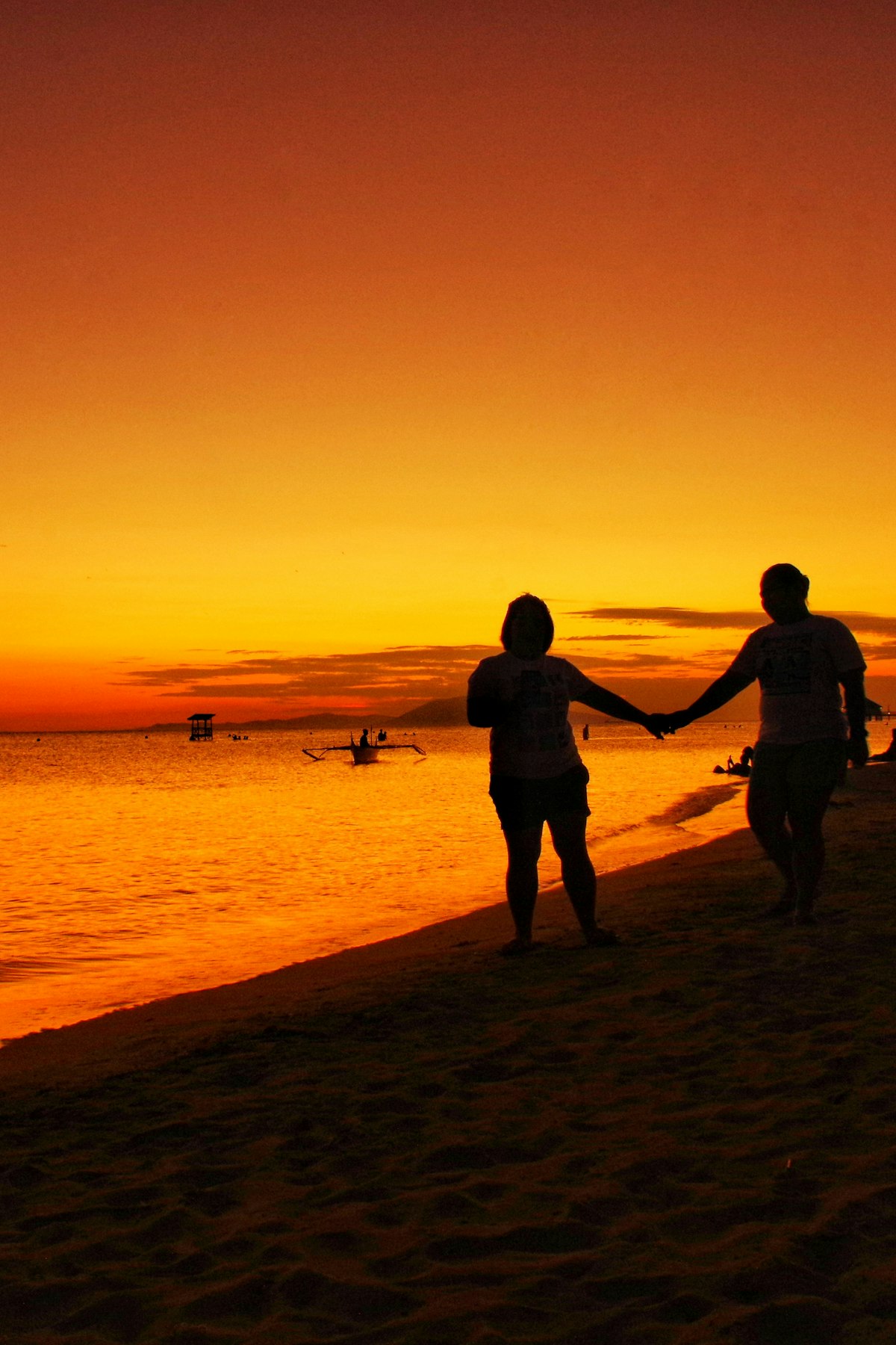 Couple holding hands on the beach at sunset